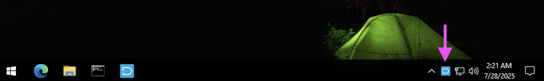 Windows taskbar at night with a pink arrow pointing to the DekkoDrive icon in the system tray, beside the network and volume icons.